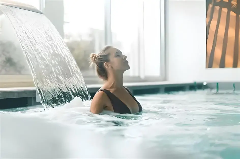 Personne nageant dans une piscine intérieure sous une cascade d’eau, ambiance détente et bien-être. 10 bienfaits du jeûne intermittent (présentation visuelle).