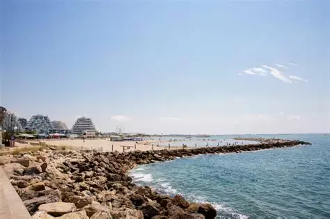 Promenade au bord de mer avec jetée en pierre et horizon clair, ambiance estivale et franche. Boisson pendant un jeûne hydrique évoquée par le cadre côtier.