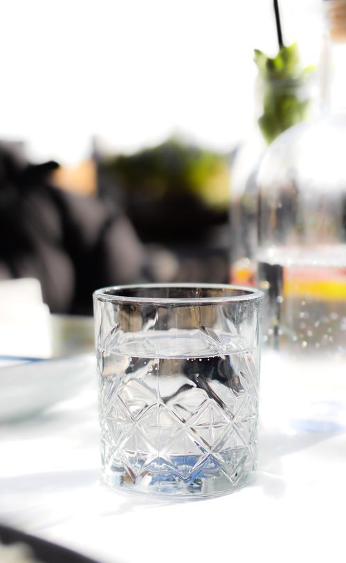 Verre d’eau clair sur une table, ambiance lumineuse et vague visibilité d’un décor flou en arrière-plan. comment faire un jeûne de 24h